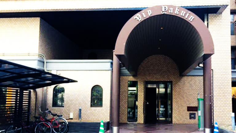 萬田うどんの右手に、丸い屋根のマンションがございます。その入口へお入りください。