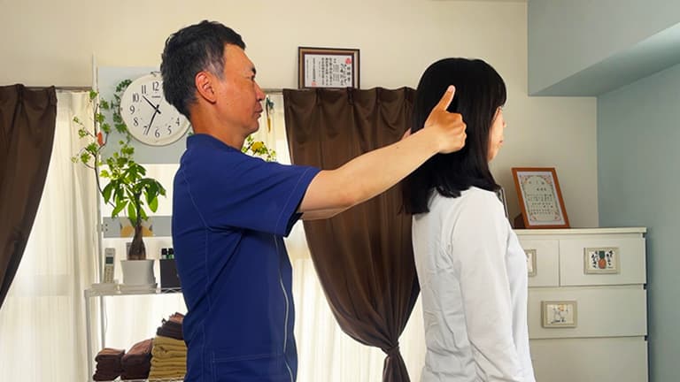整体師がお客様の姿勢や体の動きをチェックし、状態を評価している様子