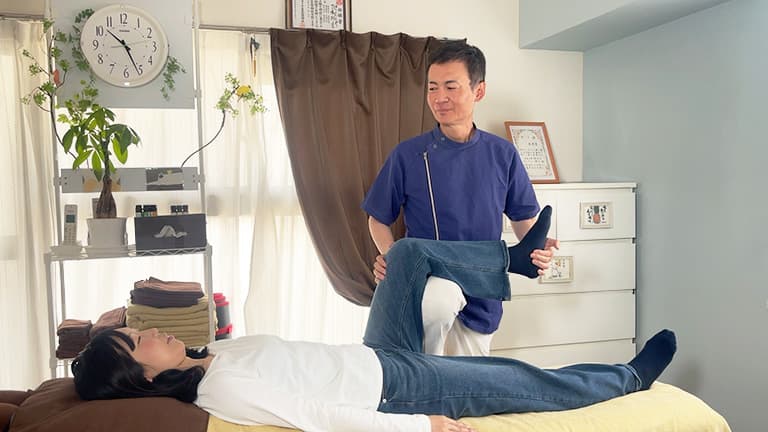 お客様が整体ベッドでリラックスし整体師が優しく施術を行っている様子